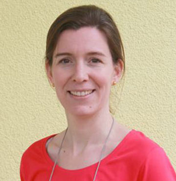 Freundliche junge Frau mit braunem Haar mit Pferdeschwanz und pinkfarbenen T-Shirt.