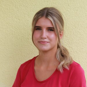 Freundliche junge Frau mit blondem Haar mit Pferdeschwanz und pinkfarbenen T-Shirt.