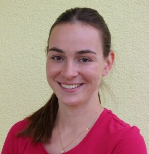 Freundliche junge Frau mit braunem Haar mit Pferdeschwanz und Nasenring und pinkfarbenen T-Shirt.